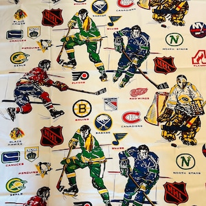 May include: A white fabric with a repeating pattern of NHL hockey team logos. The logos include the Blackhawks, Kings, Canucks, Penguins, Seals, Bruins, Canadiens, Sabres, Blues, Flyers, New York Rangers, Red Wings, North Stars, and Flames. The logos are in their team colours and are surrounded by a white background.