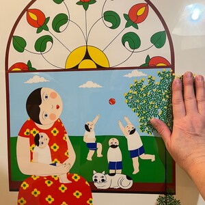 May include: A colorful illustration of a woman in a red dress with white polka dots holding a child. The woman has a red bow in her hair. There are three other children in the background playing with a ball and a cat. The illustration is set against a green background with a blue sky and white clouds.