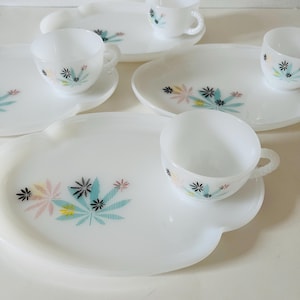 Peut inclure: Un ensemble de tasses à thé et de soucoupes blanches vintage avec des plateaux assortis. Chaque pièce présente un motif floral coloré avec des accents roses, bleus, jaunes et noirs. L'ensemble comprend plusieurs tasses, soucoupes et plateaux.