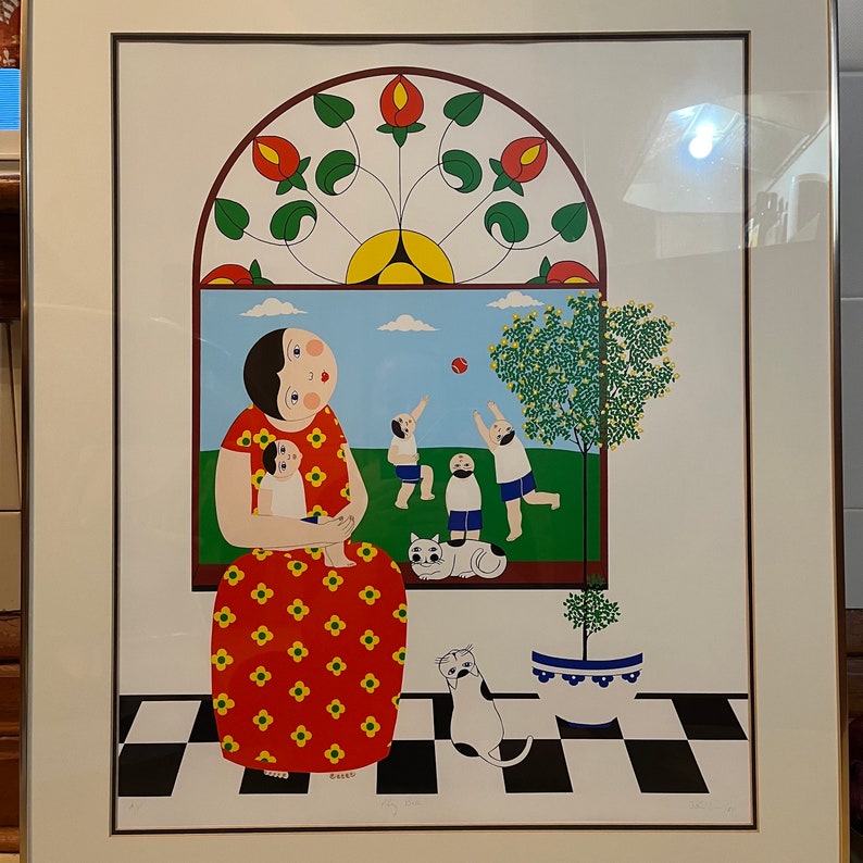 May include: A colorful framed print of a woman in a red dress holding a child. The woman is standing in front of a window with a stained glass design. There are three children playing outside the window.