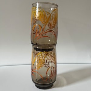Könnte beinhalten: Zwei klare Glasbecher mit braunem Farbton und einem Weizenmuster in Orange- und Gelbtönen.