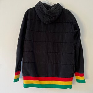 May include: Black quilted hoodie with a green, yellow, and red striped band around the bottom and cuffs.