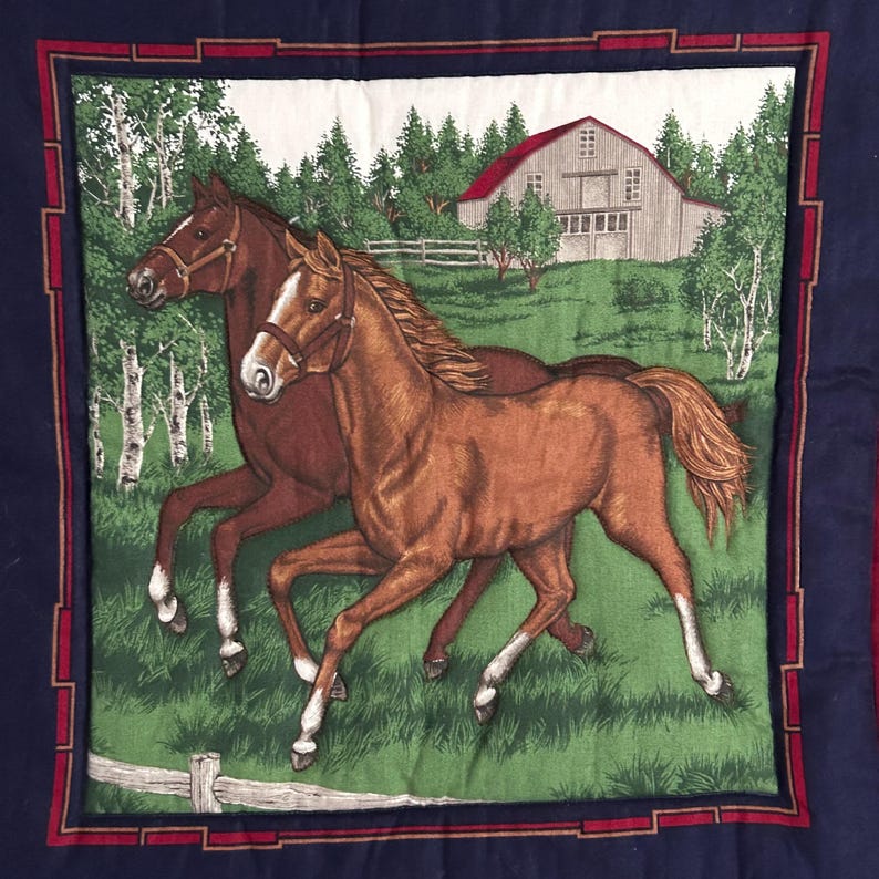 May include: A square fabric with a horse theme. Two brown horses gallop across a green field, with a barn and trees in the background. The border is dark blue with a red and white inner frame.