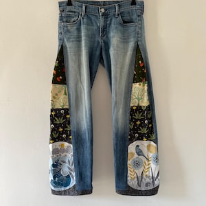 Può includere: Jeans di denim blu con pannelli di tessuto patchwork sui lati. I pannelli presentano una varietà di motivi colorati, tra cui stampe floreali, geometriche e animalier.