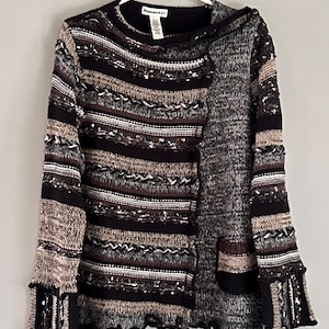 以下が含まれることがあります： 茶色、黒、白のストライプ模様のセーター。セーターは裾と袖口がフリルになっている。セーターには「Parkhurst」と書かれたタグが付いている。