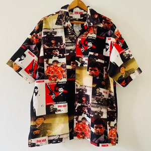 Puede incluir: Una camisa de manga corta con botones y un estampado integral colorido de caras de hombres y el texto "Spanish Harlem" y "Supreme Clothing".