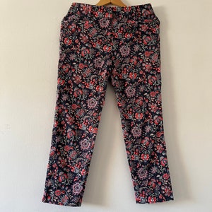 May include: Black trousers with a floral print in shades of pink, white, and green.