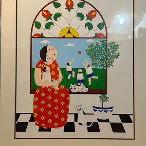 May include: A colorful lithograph print of a woman holding a child in a red and yellow patterned dress. The woman is sitting in a room with a checkered floor and a window with a stained glass design. There are two cats and two children playing outside the window.