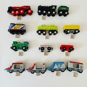 May include: A collection of ten wooden toy train cars, including a red and black steam engine, a green and black locomotive, a yellow and black flatbed car, a yellow boxcar, a green boxcar, a gray boxcar, a red boxcar, a gray and red boxcar, a gray and blue boxcar, and a gray and red boxcar. The cars are all labeled with the word "BRIO" and some have numbers on them.
