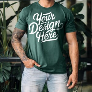 K&ouml;nnte beinhalten: Ein dunkelgr&uuml;nes T-Shirt mit dem Text "Your Design Here" in wei&szlig;en Buchstaben. Das Shirt ist aus weichem, bequemem Material und hat eine lockere Passform.