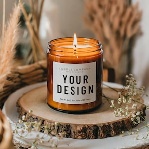 May include: A brown glass candle jar with a white label that says "CANDLE COMPANY TYPE OF CANDLE YOUR DESIGN Net Wt Bot | Burn Time of 40 hours". The candle is lit and the flame is visible.