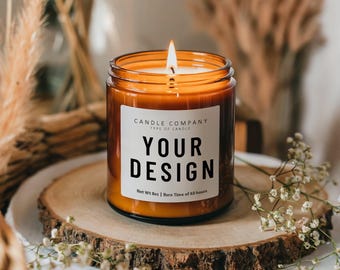 May include: A brown glass candle jar with a white label that says "CANDLE COMPANY TYPE OF CANDLE YOUR DESIGN Net Wt Bot | Burn Time of 40 hours". The candle is lit and the flame is visible.