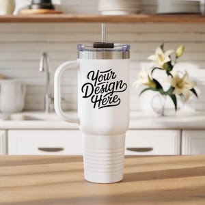 May include: White travel mug with a handle, a silver rim, and a clear lid. The mug has the text "Your Design Here" in black script. The mug is designed to hold cold or hot beverages and has a straw.