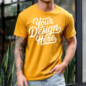 K&ouml;nnte beinhalten: Ein senfgelbes T-Shirt mit dem Text "Your Design Here" in wei&szlig;en Buchstaben.