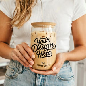 May include: A clear glass 16oz sipper glass with a bamboo lid and a straw. The glass has black text that says "Your Design Here".