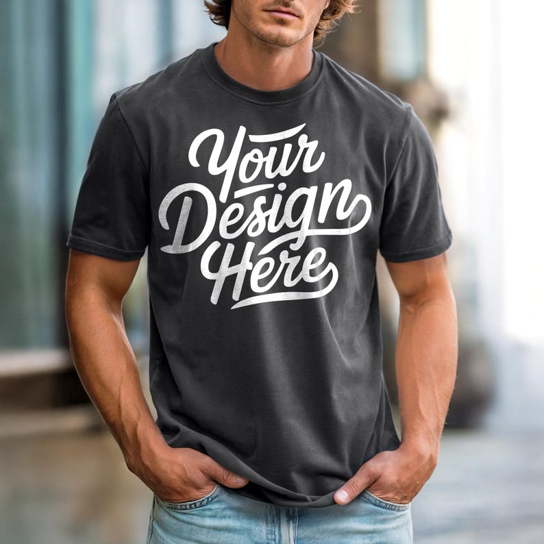 May include: Dark gray t-shirt with the text "Your Design Here" in white script. The shirt has short sleeves and a crew neck. The model is wearing blue jeans.