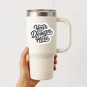 May include: White stainless steel travel mug with a black handle and a white sticker that says "Your Design Here".