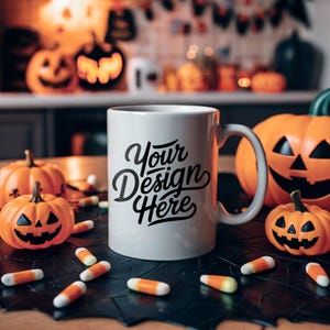 Pode incluir: Uma caneca de cerâmica branca com um design preto que diz "Your Design Here" cercada por decorações de Halloween, incluindo abóboras, milho doce e uma teia de aranha preta.