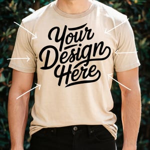 K&ouml;nnte beinhalten: Ein beiges T-Shirt mit dem Text "Your Design Here" in schwarzer Schrift.
