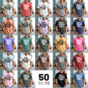 以下が含まれることがあります： 「Your Design Here」の文字がスタイリッシュに書かれた、50色のTシャツのコレクション。赤、青、緑、ピンクなど、さまざまな色合いのシャツが並び、幅広いカラーバリエーションを表現しています。