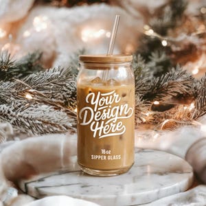 Könnte beinhalten: Ein klares 473 ml Trinkglas mit Eiskaffee, mit einem Bambusdeckel und einem durchsichtigen Strohhalm. Das Glas hat den Text "Your Design Here" in weißer Schrift. Das Glas steht auf einer Marmoroberfläche.