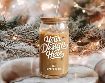 Puede incluir: Un vaso transparente de 473 ml lleno de café helado, con tapa de bambú y pajita transparente. El vaso tiene el texto "Your Design Here" en escritura blanca. El vaso está sobre una superficie de mármol.