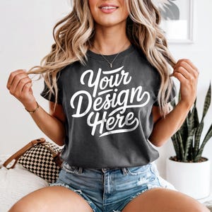 May include: A dark gray t-shirt with the text "Your Design Here" in white lettering. The shirt is made of a soft, comfortable fabric and has a relaxed fit.