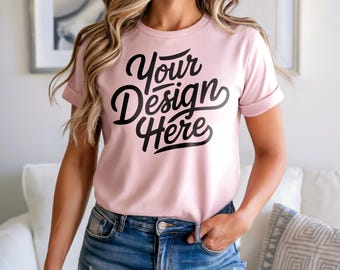 May include: A pale pink t-shirt with rolled sleeves and the text "Your Design Here" in black script. The model is wearing blue denim shorts. The shirt is a crew neck style.