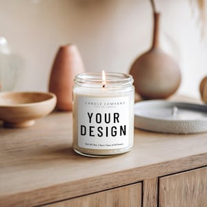 May include: A white candle with a black label that says "CANDLE COMPANY TYPE OF CANDLE YOUR DESIGN Net Wt 8oz | Burn Time of 40 hours". The candle is lit and sitting on a wooden surface.