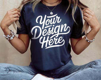 May include: A navy blue t-shirt with the text "Your Design Here" in white lettering. The shirt is being worn by a person sitting down with their legs crossed.
