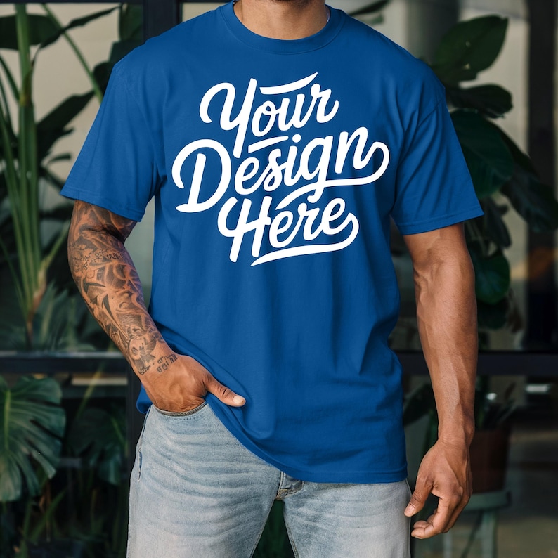 K&ouml;nnte beinhalten: Ein k&ouml;nigsblaues T-Shirt mit dem Text "Your Design Here" in wei&szlig;en Buchstaben.