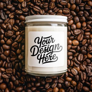 Pode incluir: Um frasco de vela branco com uma tampa branca e um rótulo que diz "Your Design Here" em um leito de grãos de café.