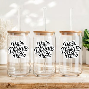 May include: Three clear glass can-shaped tumblers with bamboo lids and clear straws. Each tumbler has a black and white sticker that says "Your Design Here".