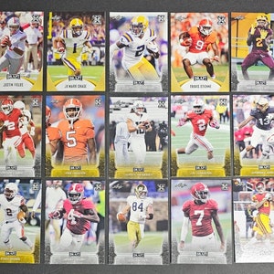 May include: A collection of 12 football trading cards featuring different players. The cards are silver and gold with a black and white design. The cards feature the players' names and numbers.