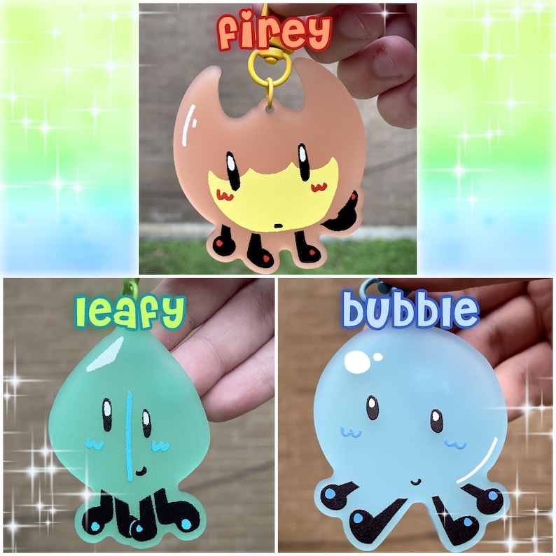 Op de afbeelding: Drie sleutelhangers met stripfiguren. De eerste is een bruin en geel vlamvormig karakter met het woord "firey" erboven. De tweede is een groen bladachtig karakter met het woord "leafy" erboven. De derde is een blauw, bubbelvormig karakter met het woord "bubble" erboven.