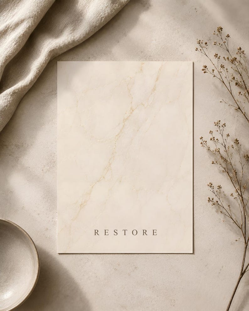 Puede incluir: Una tarjeta rectangular con un patr&oacute;n de m&aacute;rmol color crema que presenta vetas doradas sutiles. La palabra RESTORE est&aacute; impresa en una fuente sans-serif simple y oscura cerca de la parte inferior central de la tarjeta, con acabado mate.