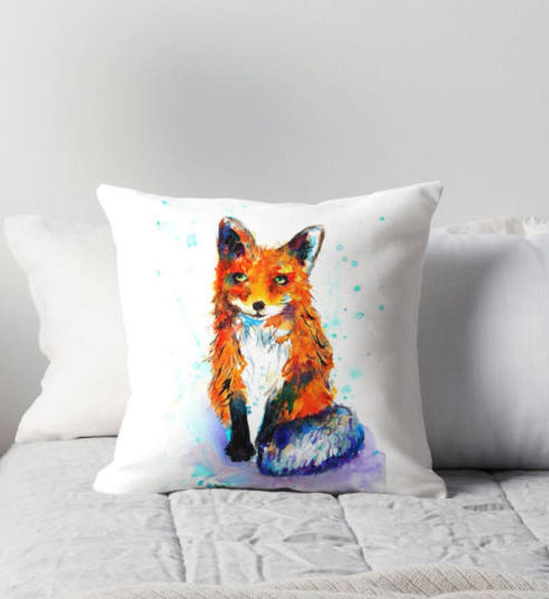 May include: A watercolor painting of a fox sitting on a white background with blue and green splatters of paint. The fox is orange and white with a bushy tail.