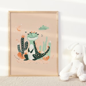 May include: A framed illustration of a green and black lizard with a friendly expression, surrounded by cacti and flowers on a peach background.