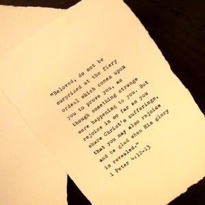 May include: A piece of off-white, textured paper with deckled edges featuring black typewriter-style text that reads: "Beloved, do not be surprised at the fiery ordeal which comes upon you to prove you, as though something strange were happening to you. But rejoice in so far as you share Christ's sufferings, that you may also rejoice and be glad when His glory is revealed." 1 Peter 4:12-13.