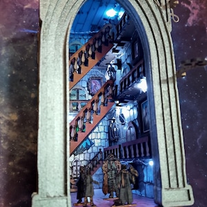 Könnte beinhalten: Ein Miniaturmodell eines Steinbogens mit einer Wendeltreppe im Inneren. Der Bogen ist mit LED-Lichtern beleuchtet und verfügt über ein Schlüsselloch mit einem Schlüssel. Das Modell ist vor einem dunkelblauen Hintergrund mit Sternen platziert.