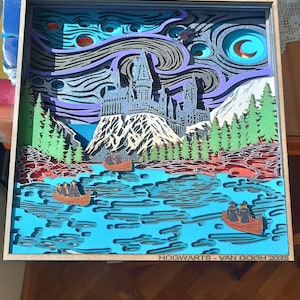 May include: A 3D papercraft artwork depicting Hogwarts castle from the Harry Potter series, styled after Vincent van Gogh's Starry Night painting. The castle is set against a swirling blue and purple sky with a crescent moon and stars. The scene includes a lake with boats and trees in the foreground. The artwork is framed in wood and has the text "HOGWARTS - VAN GOGH 2025" at the bottom.