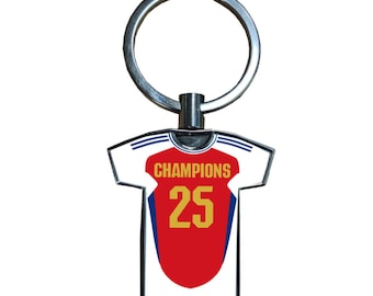 Può includere: Un portachiavi in metallo con un design a maglia bianca e rossa. La maglia ha la scritta "CHAMPIONS" in alto e il numero "25" in oro. Il portachiavi ha un anello argentato per attaccare le chiavi.