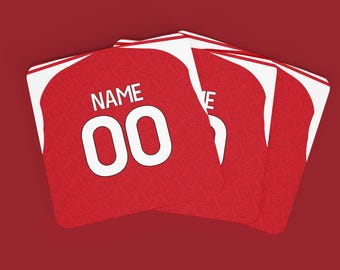 May include: Red jersey-shaped coasters with white trim and the word "NAME" above the number "00" in white. The coasters are arranged in a fan shape against a red background. The jersey design is visible.