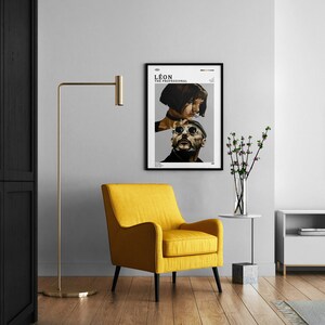K&ouml;nnte beinhalten: Ein gelber Sessel mit schwarzen Beinen steht in einem Wohnzimmer mit einem schwarzen Schrank, einer Stehlampe, einem wei&szlig;en Fernsehschrank, einem Fernseher, einem kleinen Tisch mit einer Blumenvase und einem gerahmten Poster des Films "L&eacute;on: The Professional" an der Wand.