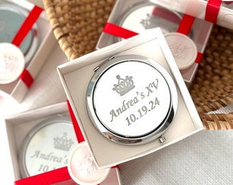 May include: White gift boxes with red ribbon and a silver compact mirror with a crown design and the text "Andrea's XV 10.19.24".