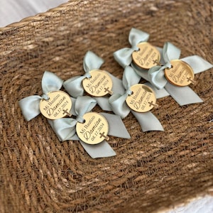K&ouml;nnte beinhalten: Ein Korb gef&uuml;llt mit goldenen runden Gef&auml;lligkeiten mit blauen Schleifen. Jede Gef&auml;lligkeit tr&auml;gt den Text "Mi Bautizo Damian 08.17.2024" und ein kleines Kreuz.