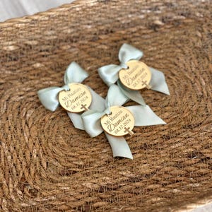 K&ouml;nnte beinhalten: Ein Korb gef&uuml;llt mit hellblauen und goldenen Taufgeschenken. Jedes Geschenk ist ein kleiner Holzkreis mit dem Text "Mi Bautizo Damian 08.17.2024" und einem kleinen goldenen Kreuz.