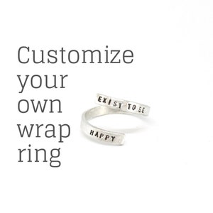 May include: Silver wrap ring with the words "Exist to be happy" engraved on it.