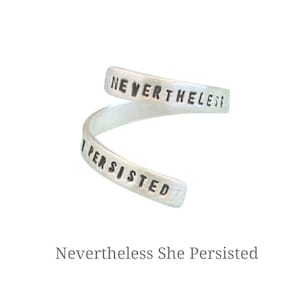 Könnte beinhalten: Ein silberner Ring mit der Gravur "Nevertheless She Persisted".