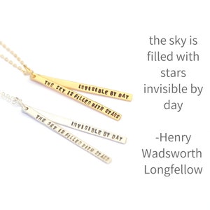 Puede incluir: Dos collares de plata y oro con un colgante de barra que dice "The sky is filled with stars invisible by day" - Henry Wadsworth Longfellow.